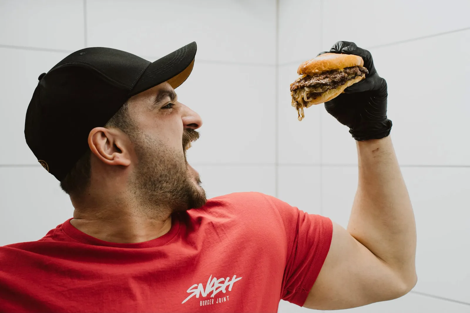 Mitarbeiter im SNASH-Shirt beißt in einen frisch gesmashten Double-Burger